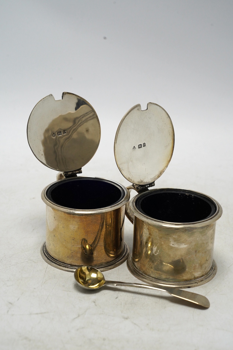 A pair of George V silver drum mustards, by Harman & Co, London 1929, 70mm, one with associated spoon. Condition - fair